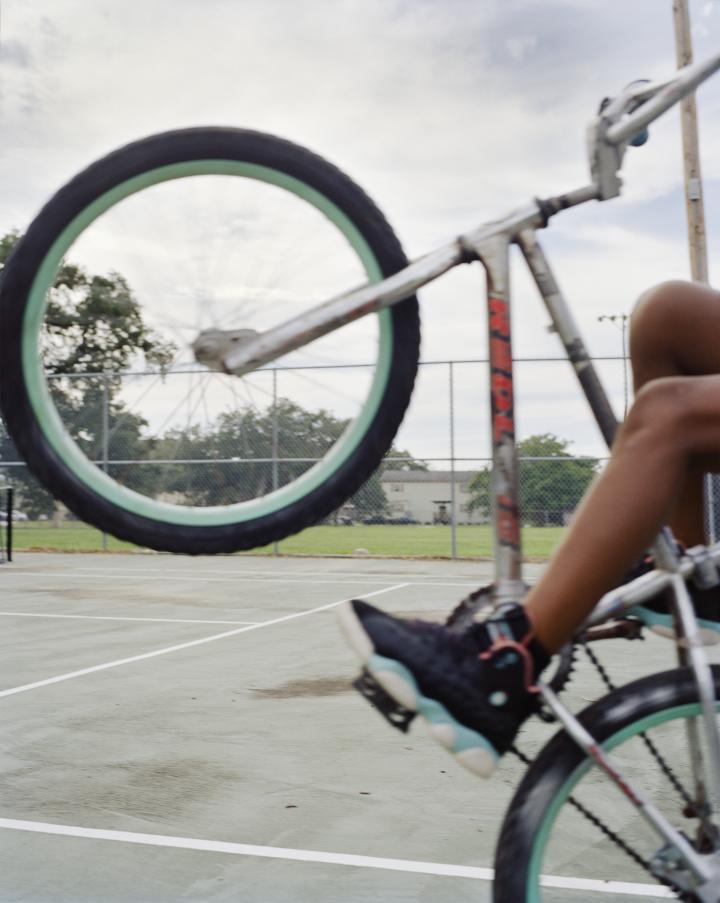 A young boy popping a wheelie on a bike. 