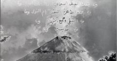 A black and white mountain with arabic superimposed over it. 