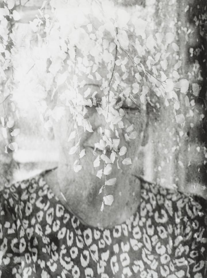 An old woman surrounded by bright white leaves. 