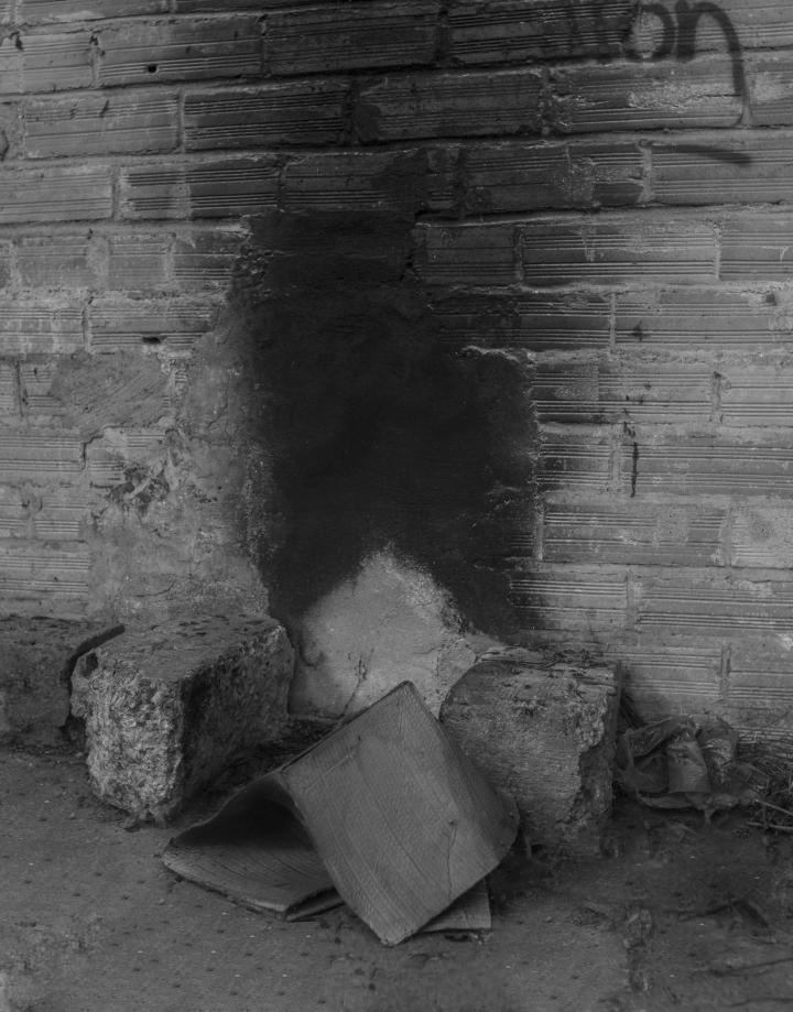 A black and white photo of a concrete wall and concrete rubble. 