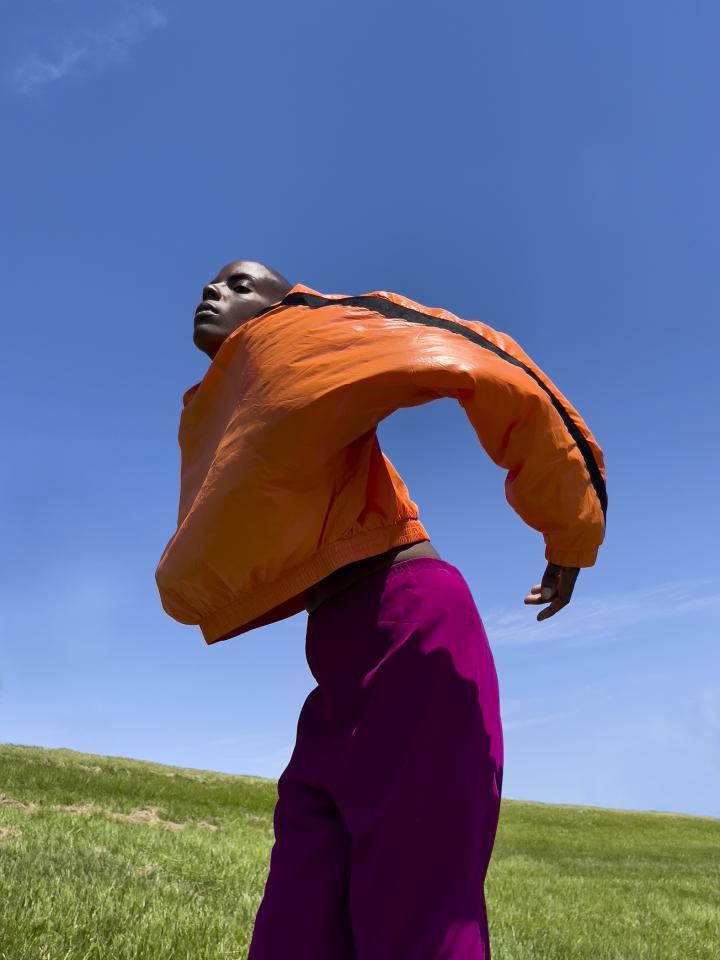 A kid outside with an orange jacket.