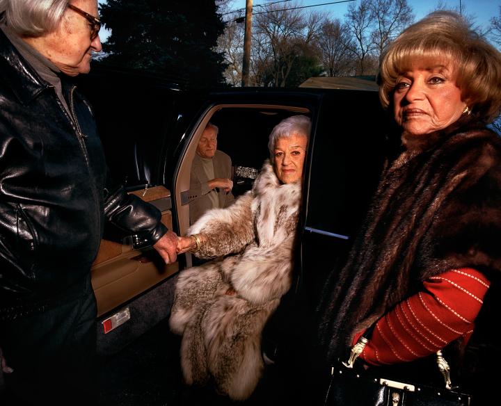 An elderly lady being helped out of a car.