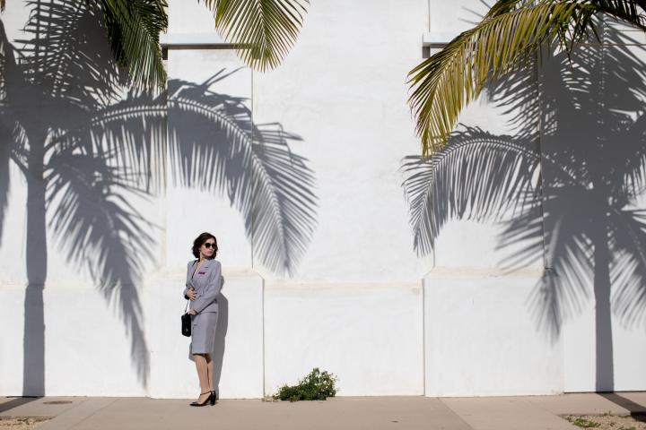 A woman outside with trees on each side.