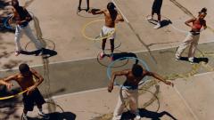 Kids outside playing with a hula hoop.