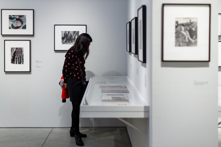 A woman looking down at a glass case at a ICP exhibit. 