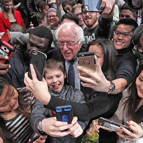 A crowd of people taking picture with a person.